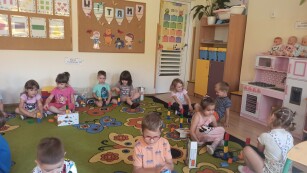 dzieci siedzą na dywanie i patrzą na swoje klocki