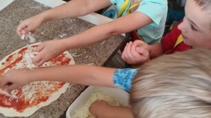 dzieci dekorują pizzę