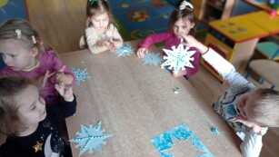 zadowolone dzieci wyklejają śnieżynki za pomocą plasteliny