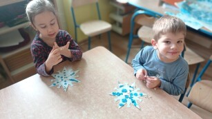 chłopiec i dziewczynka wyklejają śnieżynki plasteliną