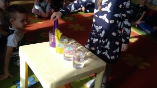 Wędrująca woda- dziewczynka wkłada kawałki kolorowej bibuły do kubeczków