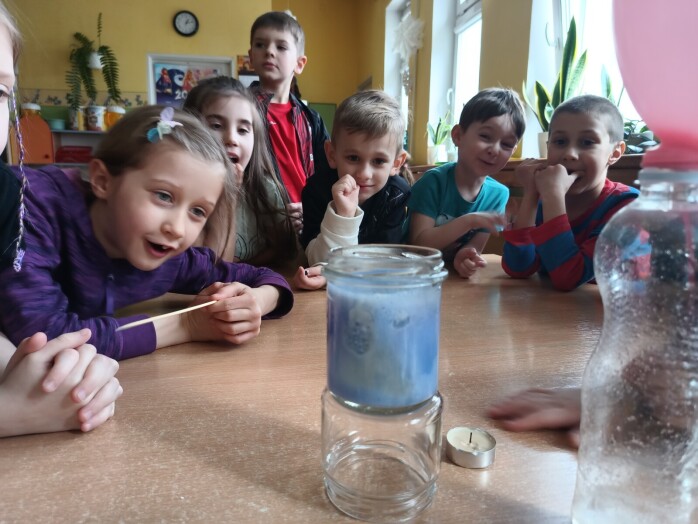 Dzieci patrzą na słoik napełniony sodą, farbą i olejem