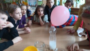 Dzieci patrzą eksperyment butelki z wodą napełnioną wodą oraz nałożony na nią balon