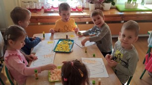 Dzieci wyklejają żółtym papierem literę W